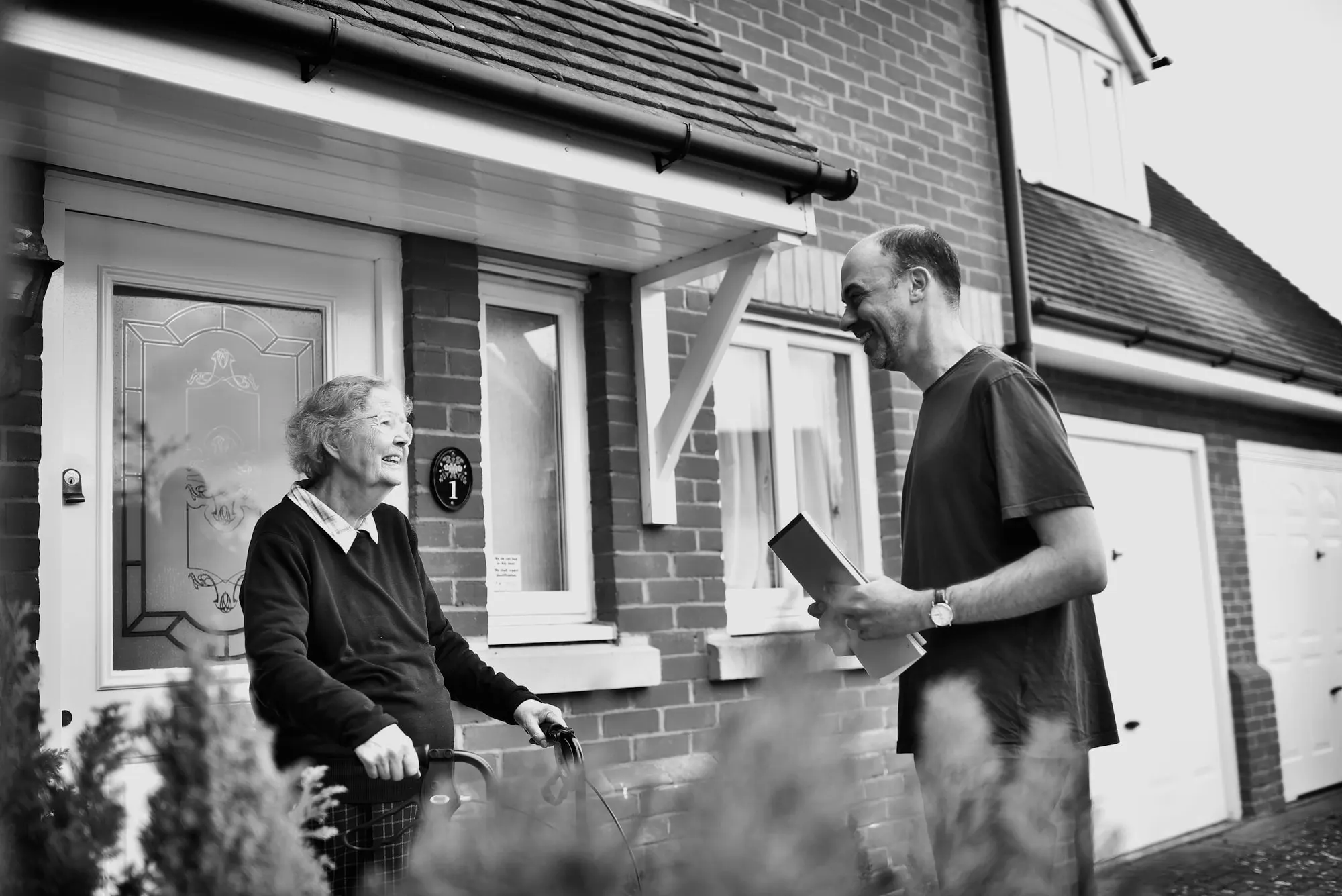A volunteer talking with an older resident at her front door.