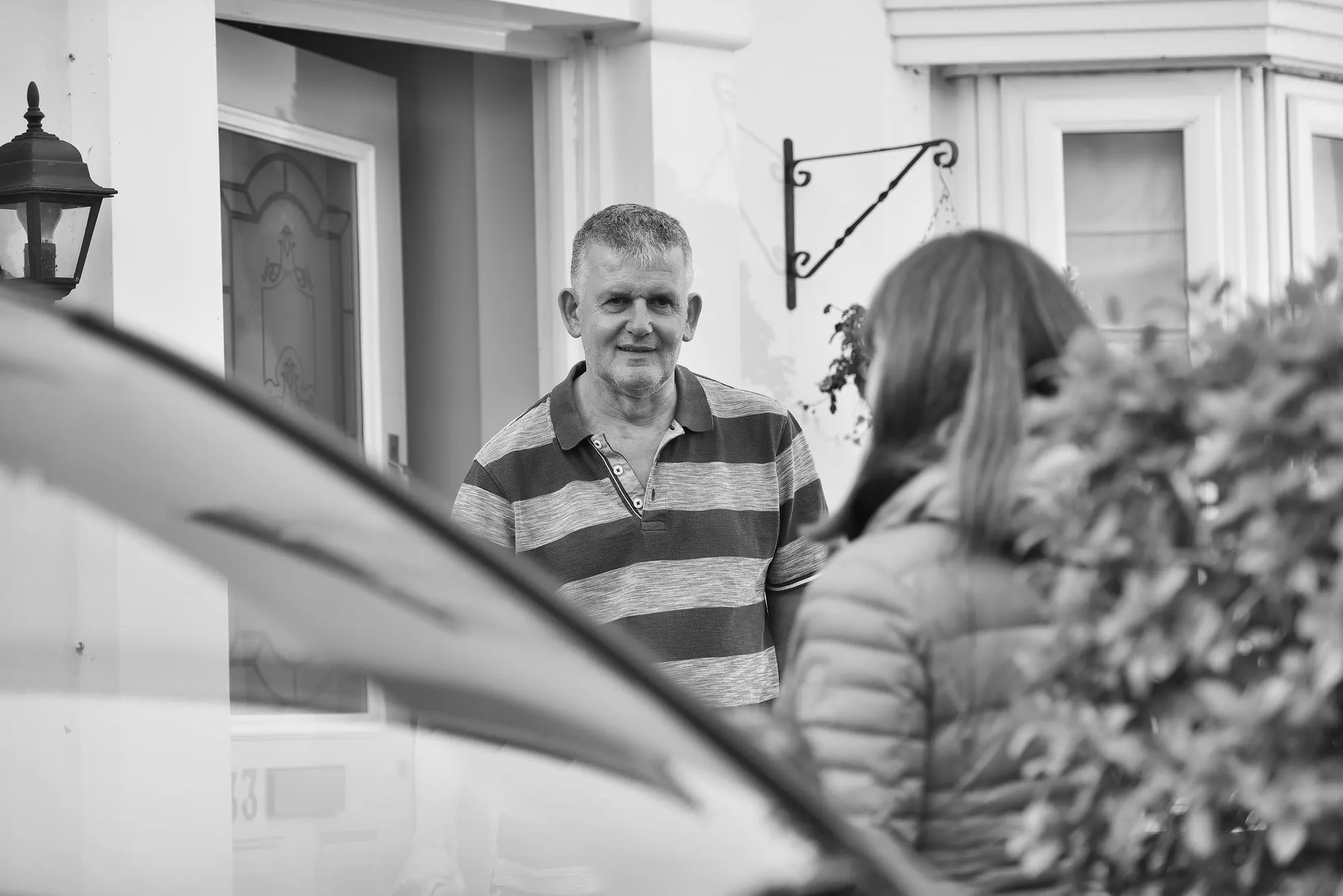 A volunteer driver talking with a passenger outside her front door.
