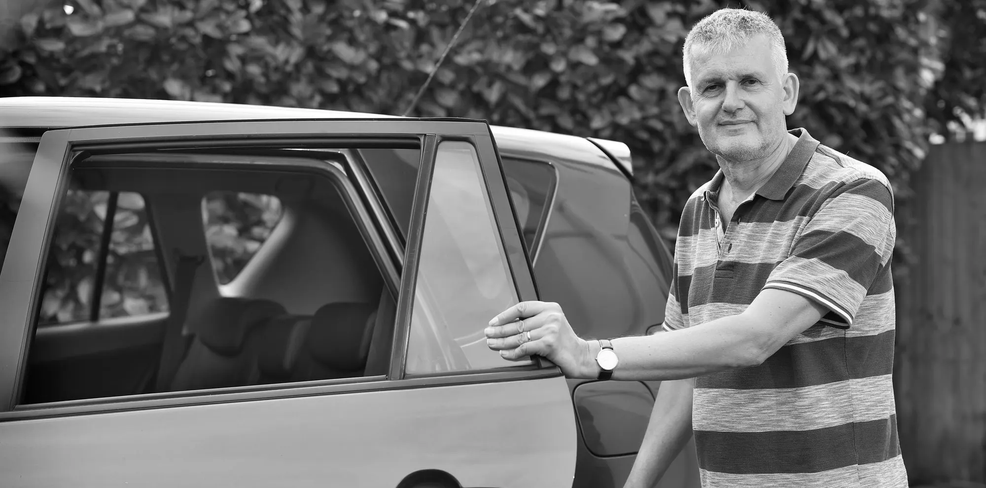 A volunteer driver standing beside his car.